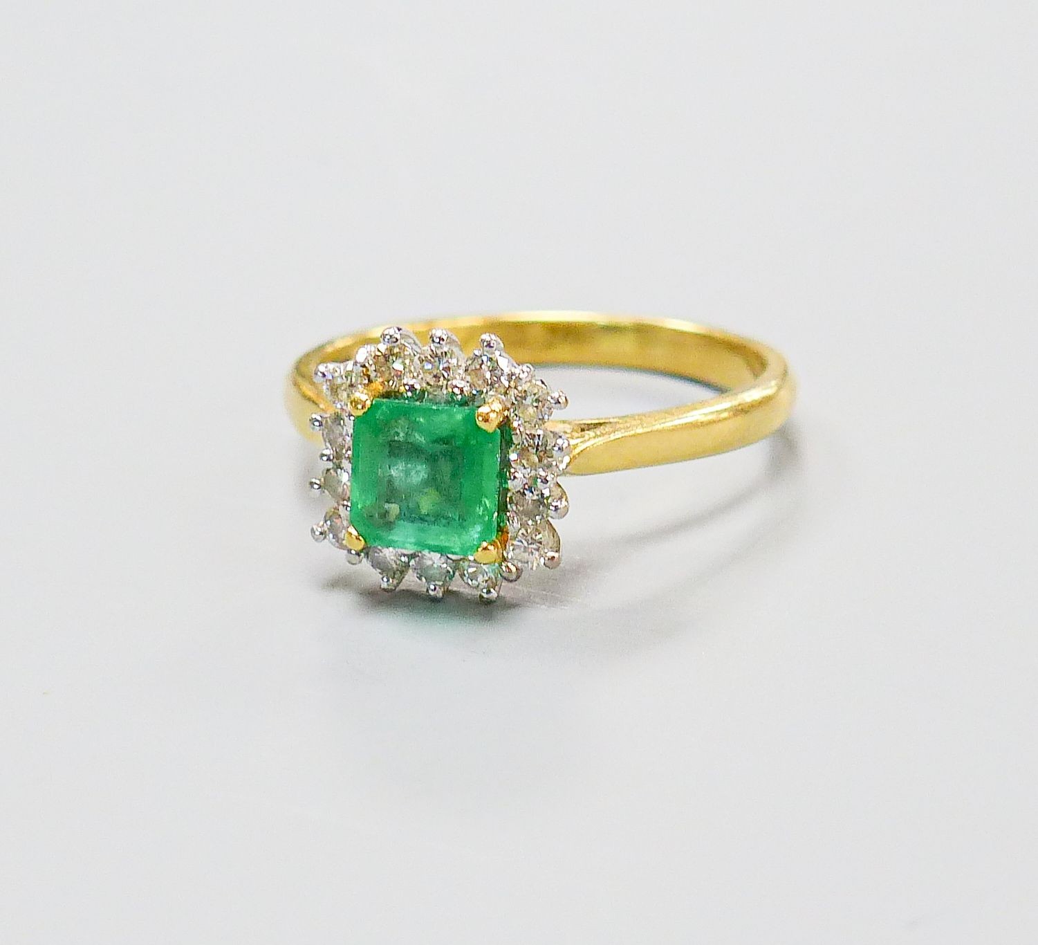 A modern 18ct gold, emerald and diamond set square cluster ring, size O, gross weight 4.3 grams.